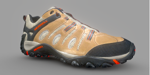 A single beige and black trail running shoe with red accents against a gray background.