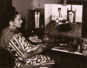 Kahlo photographed seated on her wheelchair, painting her 'Self-Portrait with the Portrait of Doctor Farrill', 1951. 